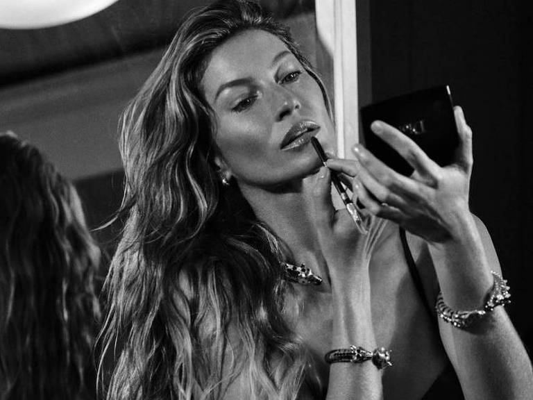 A top model Gisele Bündchen aparece retocando o batom em foto PB de um editorial de moda 