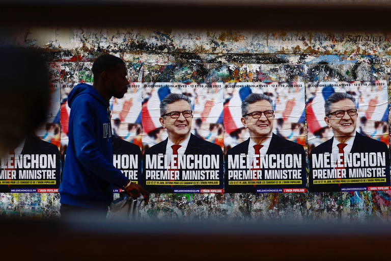 Pedestre passa em frente a cartazes da campanha de Jean-Luc Mélenchon, líder da França Insubmissa, para as eleições legislativas, em Paris