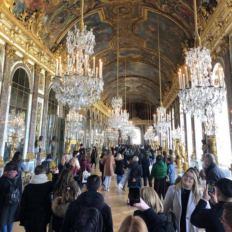 Turistas observam pinturas do Palácio de Versalhes, na França
