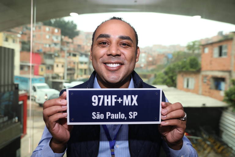 Presidente do G10 das Favelas, Gilson Rodrigues, segura a placa com o Plus Code da sede da organização