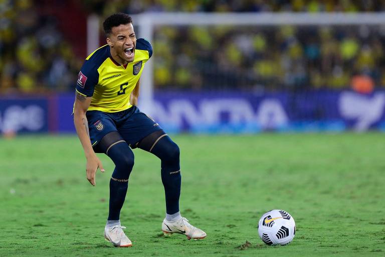 O lateral direito equatoriano Byron Castillo, sozinho na jogada e com a bola à sua frente, dá um grito em jogo contra a Bolívia; ele usa camisa amarela e calções azul-escuros