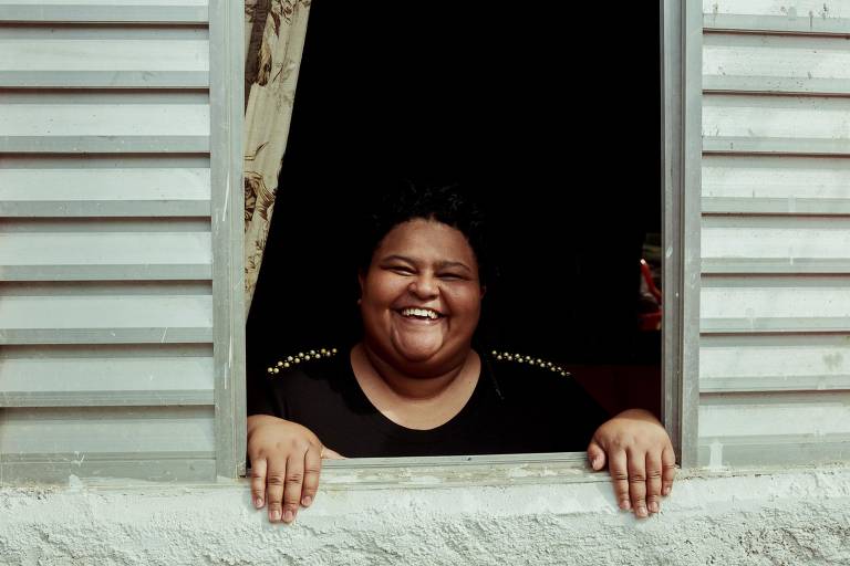 mulher sorrindo sobre janela de sua casa
