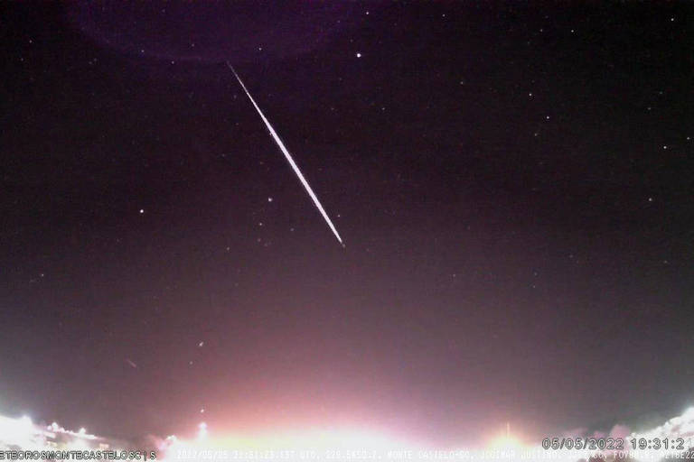 imagem de noite com meteoro cortando o céu e pontos de luz