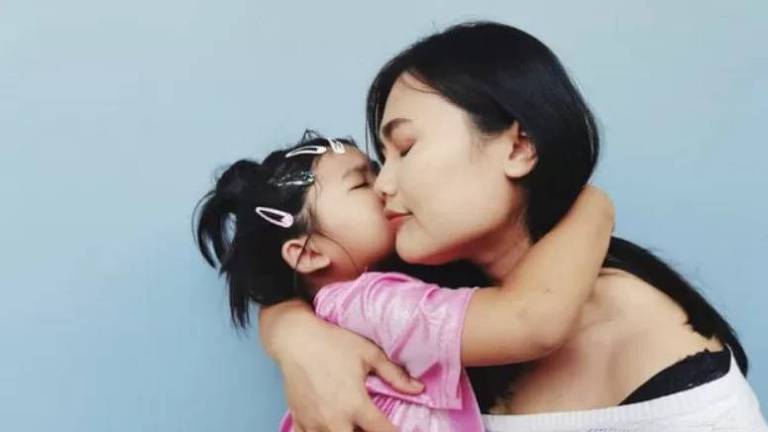 Mãe é abraçada e beijada pela filha