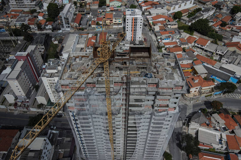 Imagem mostra prédio em construção, em meio a casas, ruas e outros prédios menores.