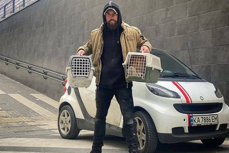 Alexei Surovtsev segura duas gaiolas com gatos resgatados em Irpin, na Ucrânia