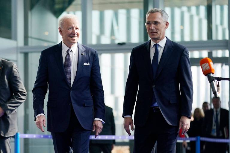Dois homens de terno e gravata caminham; à esquerda o presidente americano Joe Biden e à direita, o secretário-geral da OTAN, Jens Stoltenberg