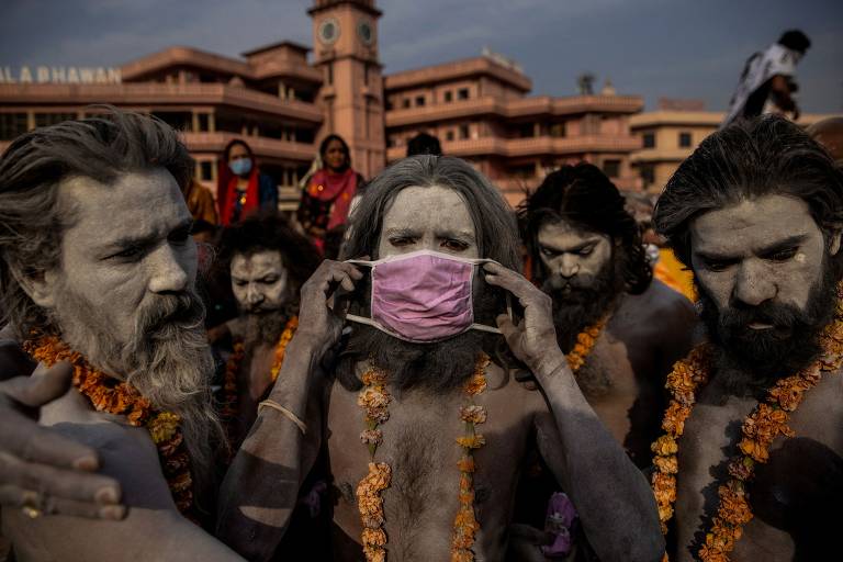 Um 'Naga Sadhu' coloca uma máscara no rosto antes de entrar no rio Ganges, no festival Kumbh Mela, em Haridwar, na Índia