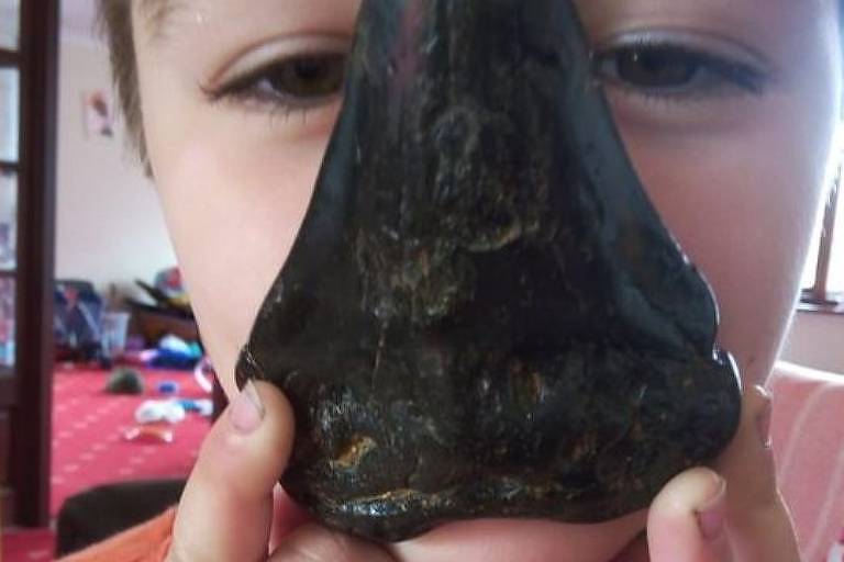 Criança segura em frente ao rosto dente de tubarão