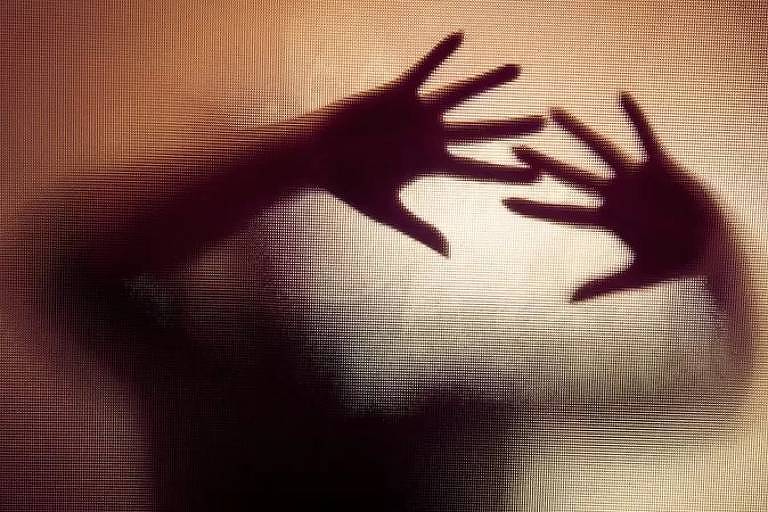 Imagem mostra a sombra de uma pessoa com as mãos espalmadas