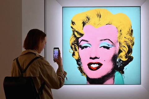 (FILES) In this file photo taken on April 29, 2022 a woman takes a photo of Andy Warhol's 'Shot Sage Blue Marilyn' during Christie's 20th and 21st Century Art press preview at Christie's New York in New York City. - An iconic portrait of Marilyn Monroe by American pop art visionary Andy Warhol went under the hammer for a record $195 million on May 9, 2022 at Christie's, becoming the most expensive 20th century artwork ever sold at public auction.
