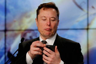 FILE PHOTO: Elon Musk looks at his mobile phone during a post-launch news conference to discuss the  SpaceX Crew Dragon astronaut capsule in-flight abort test at the Kennedy Space Center