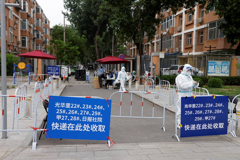 Trabalhadores com roupas de proteção são vistos em uma entrada bloqueada de área residencial em lockdown em Pequim; a China mantém a política de Covid zero, com controle rígido para evitar mais contaminação pelo coronavírus