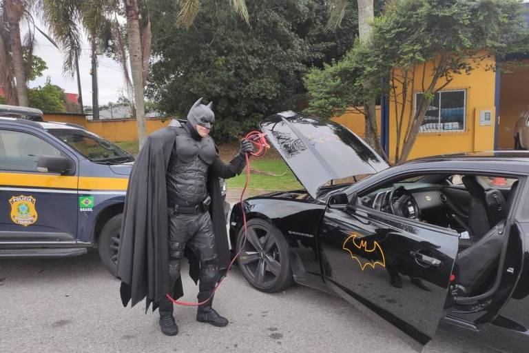 Homem vestido de Batman e seu 'batmóvel'