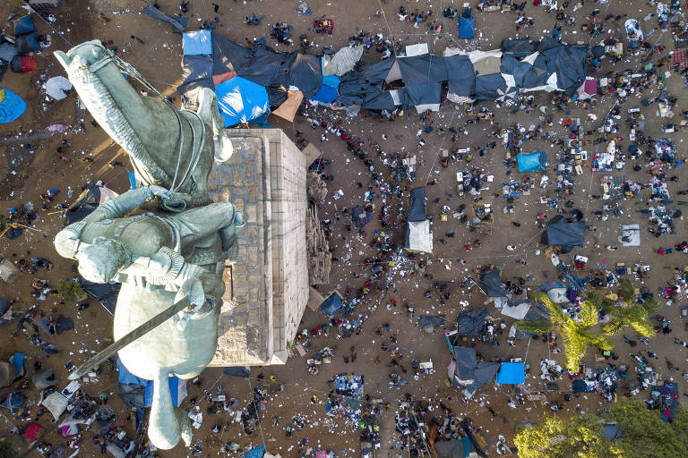 Foto da praça Princesa Isabel, no centro de São Paulo, vista de cima. Vê-se um monumento que fica na praça cercado pelo fluxo de moradores de rua e dependentes químicos, além disso, vê-se também barracas e muito lixo  