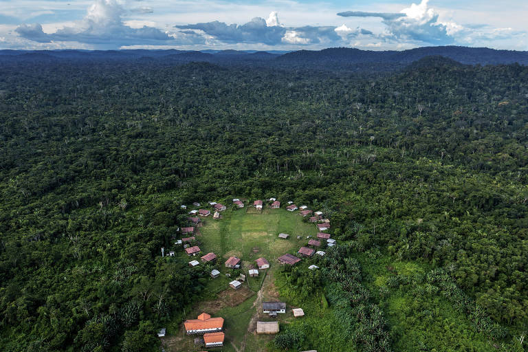 Vista aérea de um grupo de casas construídas em círculo, deixando um pátio redondo no meio delas, em meio a uma área de floresta
