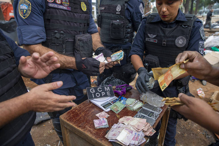 Guardas-civis metropolitanos apresentam objetos e dinheiro apreendidos durante a ação na cracolândia