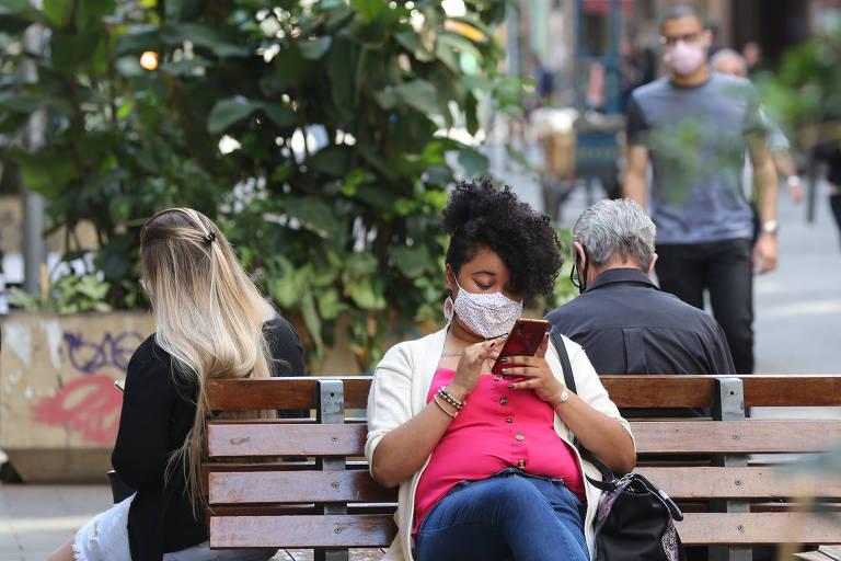 Mulher usa o celular em praça no centro de São Paulo
