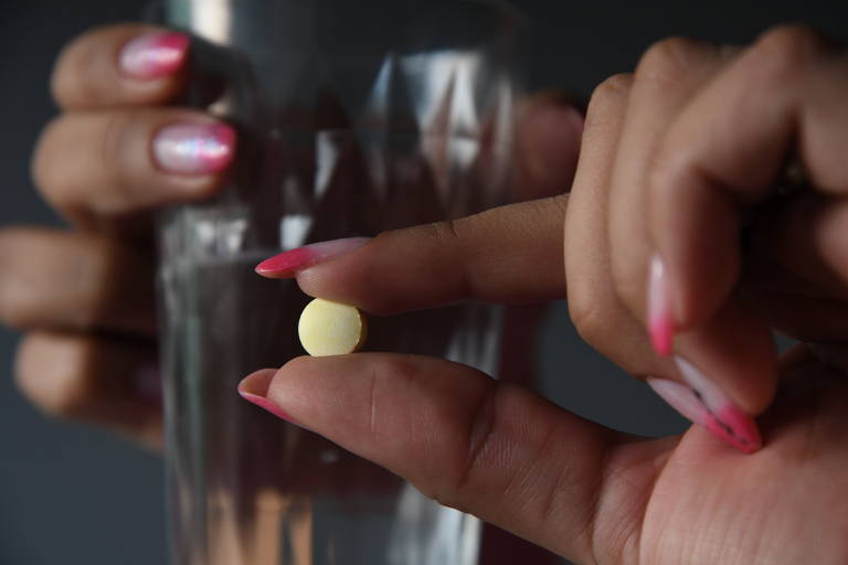 Foto mostra mão de mulher que segura pílula