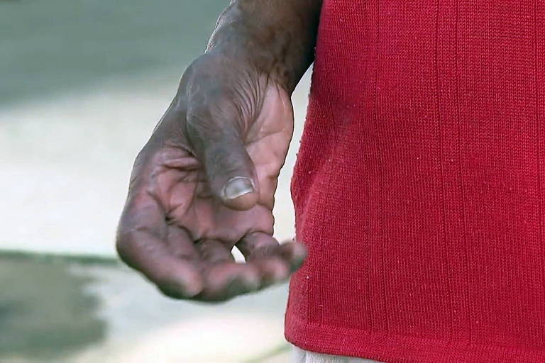 detalhe de mão de idosa negra com blusa vermelha