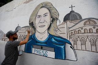 A man participates in drawing a mural of Al Jazeera reporter Shireen Abu Akleh in the Gaza Strip