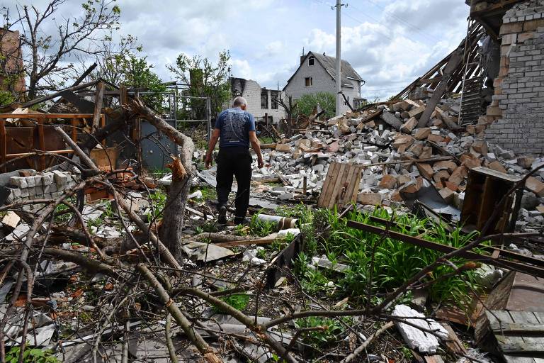 Homem anda pelos restos de sua casa em Mala Rogan, aldeia a leste de Kharkiv