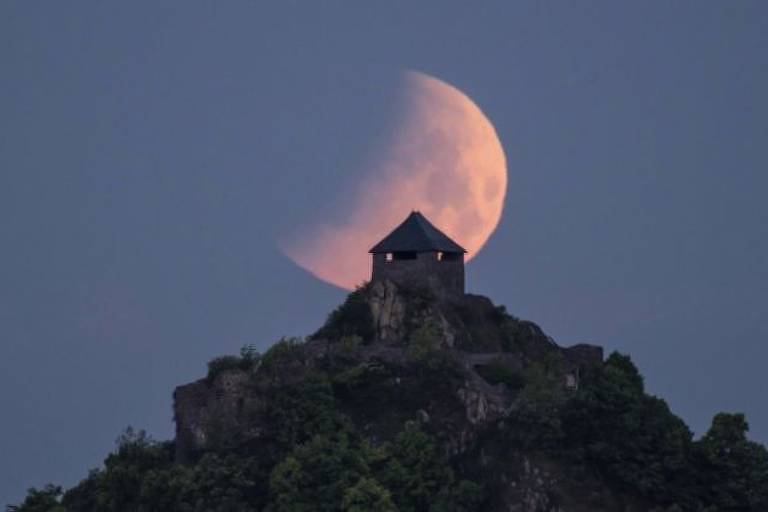 Imagem panorâmica mostra uma casa no alto de uma montanha e a lua