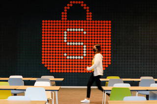 FILE PHOTO: A person walks in front of a Shopee sign at its office in Singapore