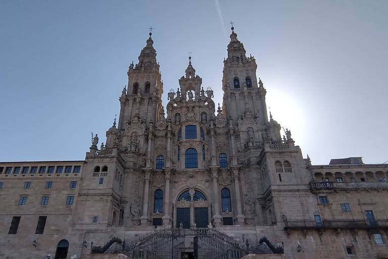 A catedral, um edificío gótico e româmico, de tijolos claros, com a luz do sol ao fundo