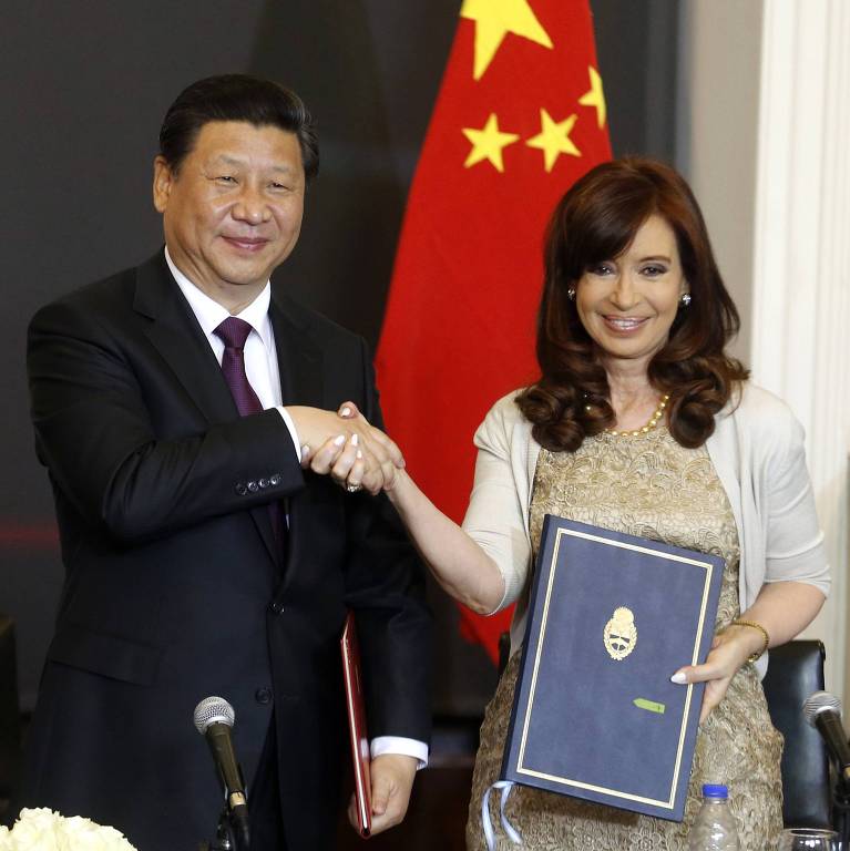 A então presidente da Argentina, Cristina Kirchner, cumprimenta o presidente da China, Xi Jinping, na Casa Rosada, em Buenos Aires; atrás dele há uma bandeira da China