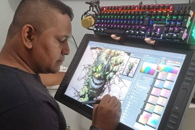 Homem negro pinta desenho de verde em tela de computador