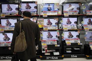 A man looks at television screens with reports on the death of Kim Jong-il, at an electronics store in Tokyo