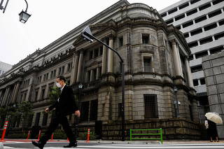 FILE PHOTO: A man wearing a protective mask walks past the headquarters of Bank of Japan amid the coronavirus disease (COVID-19) outbreak in Tokyo