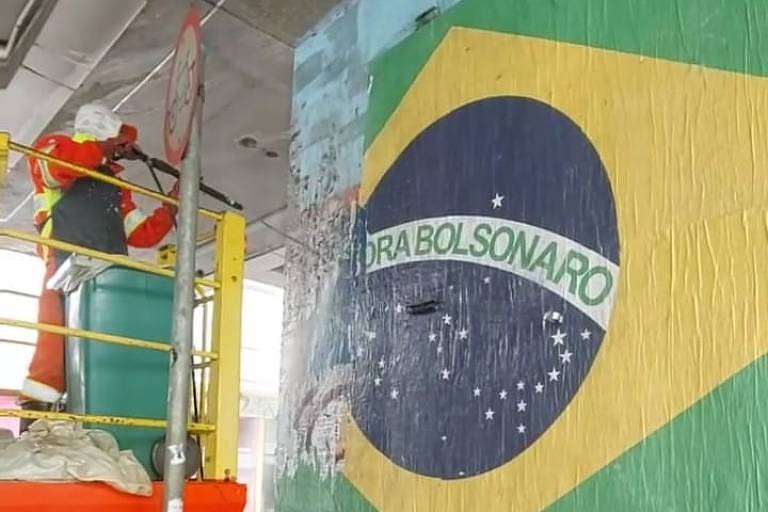 faxineiro limpando uma coluna com a bandeira do brasil fraseada com Fora Bolsonaro