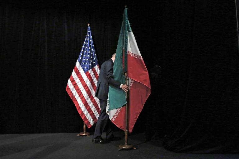 Funcionário remove as bandeiras de EUA e Irã de palco após foto com chanceleres e representantes de EUA, Irã, China, Rússia e Reino Unido, Alemanha, França e União Europeia em Viena, na Áustria