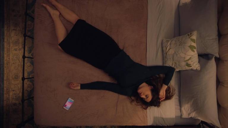 Eve Fletcher, interpretada por Kathryn Hahn, está deitada em uma cama em cena da série 'Mrs. Fletcher', disponível na HBO Max
