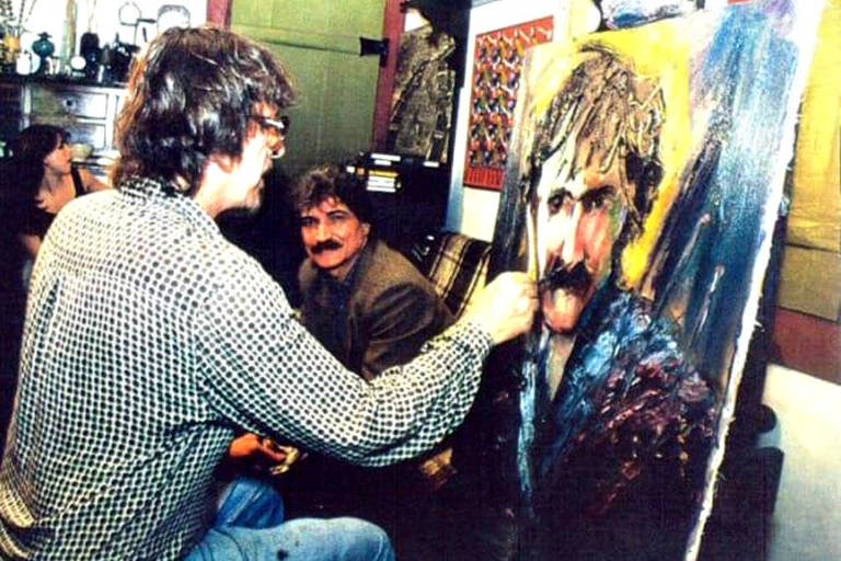 O artista plástico Carlos Bracher pintando um retrato do cantor Belchior, que está ao fundo 