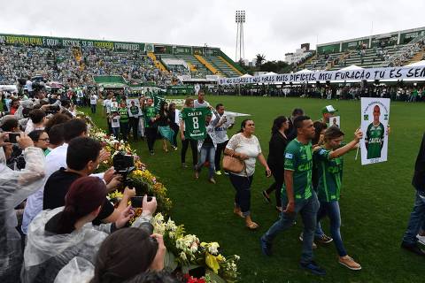 Relatives of the members of the Chapecoense Real football club team killed in a plane crash in Colombia enter the field during a funeral ceremony at the stadium in  Chapeco, Santa Catarina, southern Brazil, on December 3, 2016.  The bodies of 50 players, coaches and staff from a Brazilian football team tragically wiped out in a plane crash in Colombia arrived home Saturday for a massive funeral. / AFP PHOTO / Nelson Almeida