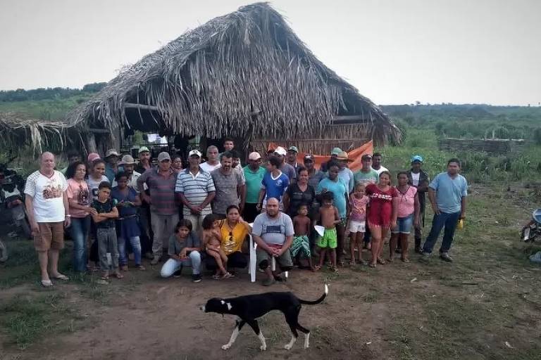 Um grupo de pessoas da mesma família posa para foto em frente a uma casa em uma área rural