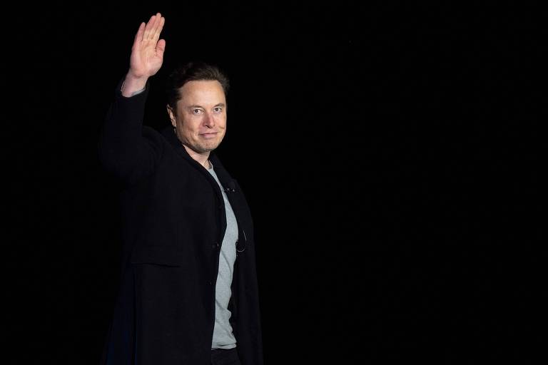 Elon Musk (50) acena em frente a fundo preto