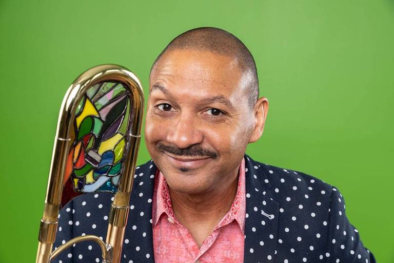 Em foto colorida, o trombonista Delfeayo Marsalis posa para a câmera sorrindo e segurando seu instrumento