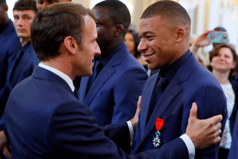 O presidente francês Emmanuel Macron (à esq.) abraça Kylian Mbappe durante cerimônia em que os jogadores campeões mundiais de 2018 receberam a medalha de Legião da Honra