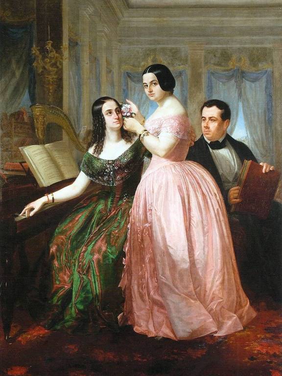 Dentro uma sala, o maestro Francisco é registrado em segundo plano, enquanto olha para duas mulheres que estão em destaque. Uma delas está de pé e outra está sentada em frente a um piano, ouvindo as notas que o maestro dita.