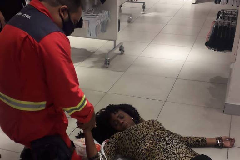 mulher negra desmaiada em chão de loja é atendida por socorrista