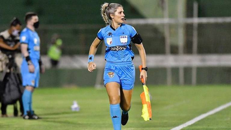Com uniforme todo azul e bandeira quadriculada na mão esquerda, a bandeirinha Neuza Back corre na lateral do campo em Guarani x São Paulo no Campeonato Paulista de 2022