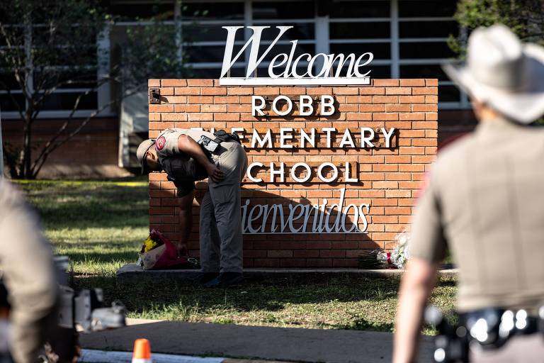 Policial deposita flores para vítimas do massacre em escola em Uvalde, no Texas