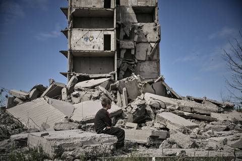TOPSHOT - A young boy sits in front of a damaged building after a strike in Kramatorsk in the eastern Ukranian region of Donbas, on May 25, 2022. (Photo by ARIS MESSINIS / AFP)