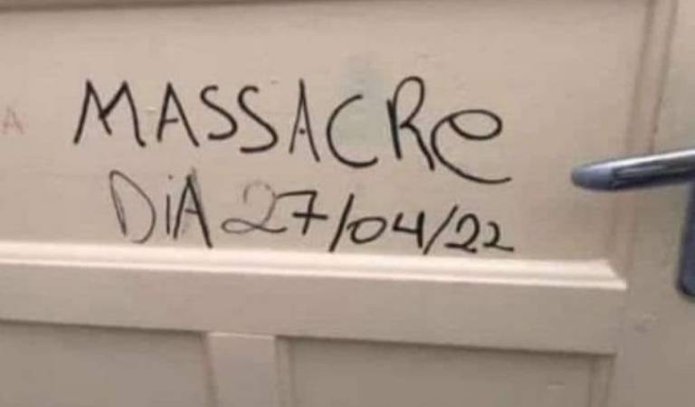 Pichação em porta branca, feita com caneta preta diz: Massacre Dia 27/04/22"