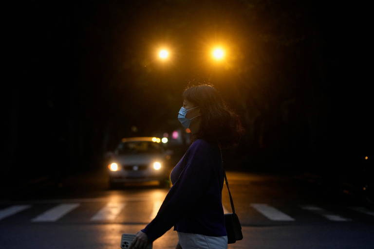 Jovem de máscara em faixa de pedestres de Xangai
