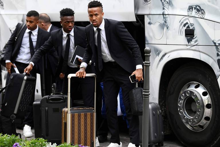 Usando traje social e com malas próximas a eles, Militão, Vini Jr. e Rodrygo, do Real Madrid, chegam a hotel na França, onde a equipe enfrentará o Liverpool na decisão da Champions League